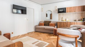 Ein modernes Wohnzimmer mit einer Couch, einem Esstisch und einem Fernseher.