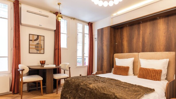 Ein Schlafzimmer mit einem großen Bett, einem Holz-Kopfteil und einem kleinen Tisch mit Stühlen.