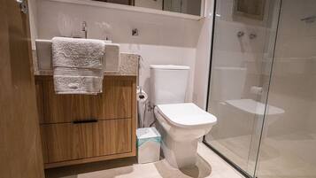 A modern bathroom with a wooden vanity, a toilet, and a glass shower enclosure.