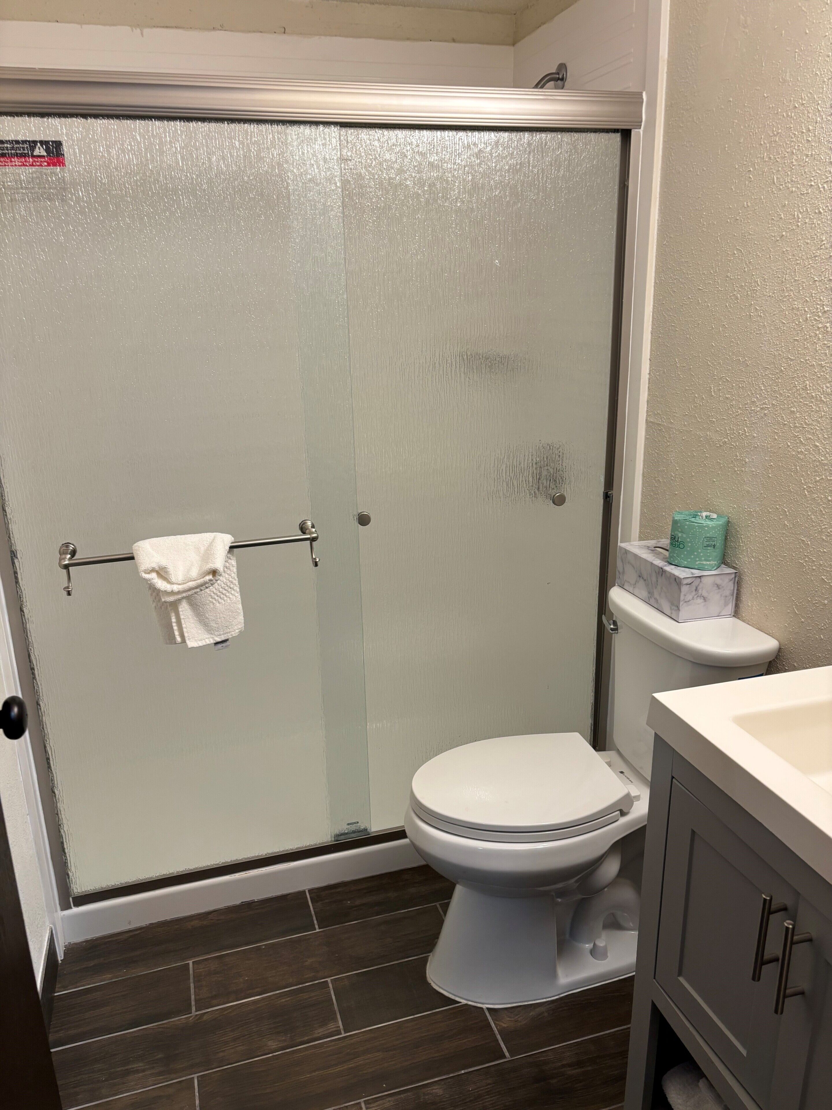 Une salle de bain avec douche, toilettes et lavabo.