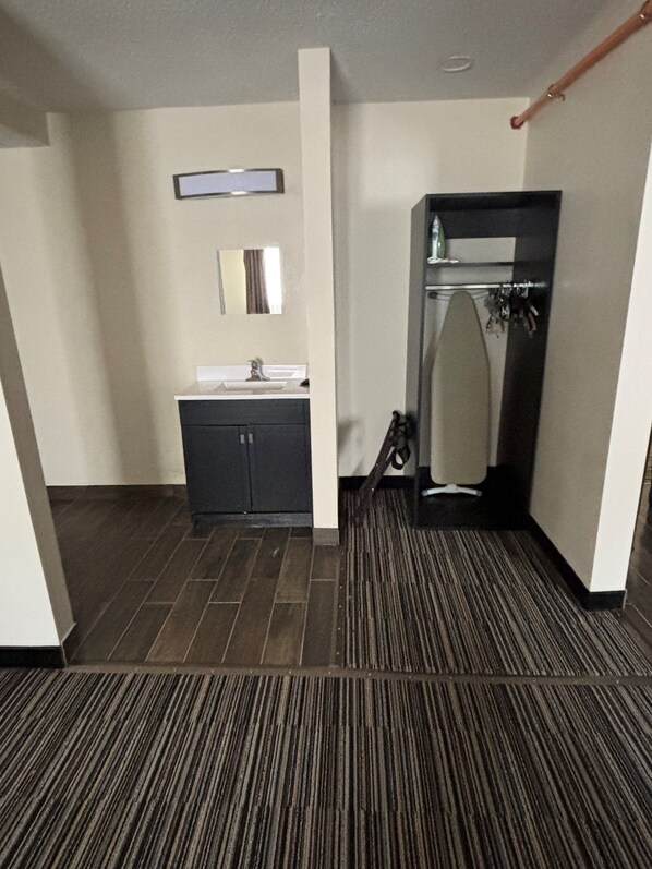 A hotel bathroom with a sink, mirror, and shower.