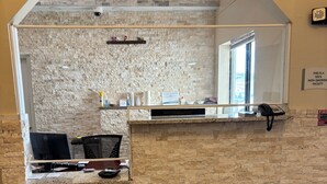 Zona de recepción con pared de piedra, una computadora, un teléfono y una ventana.