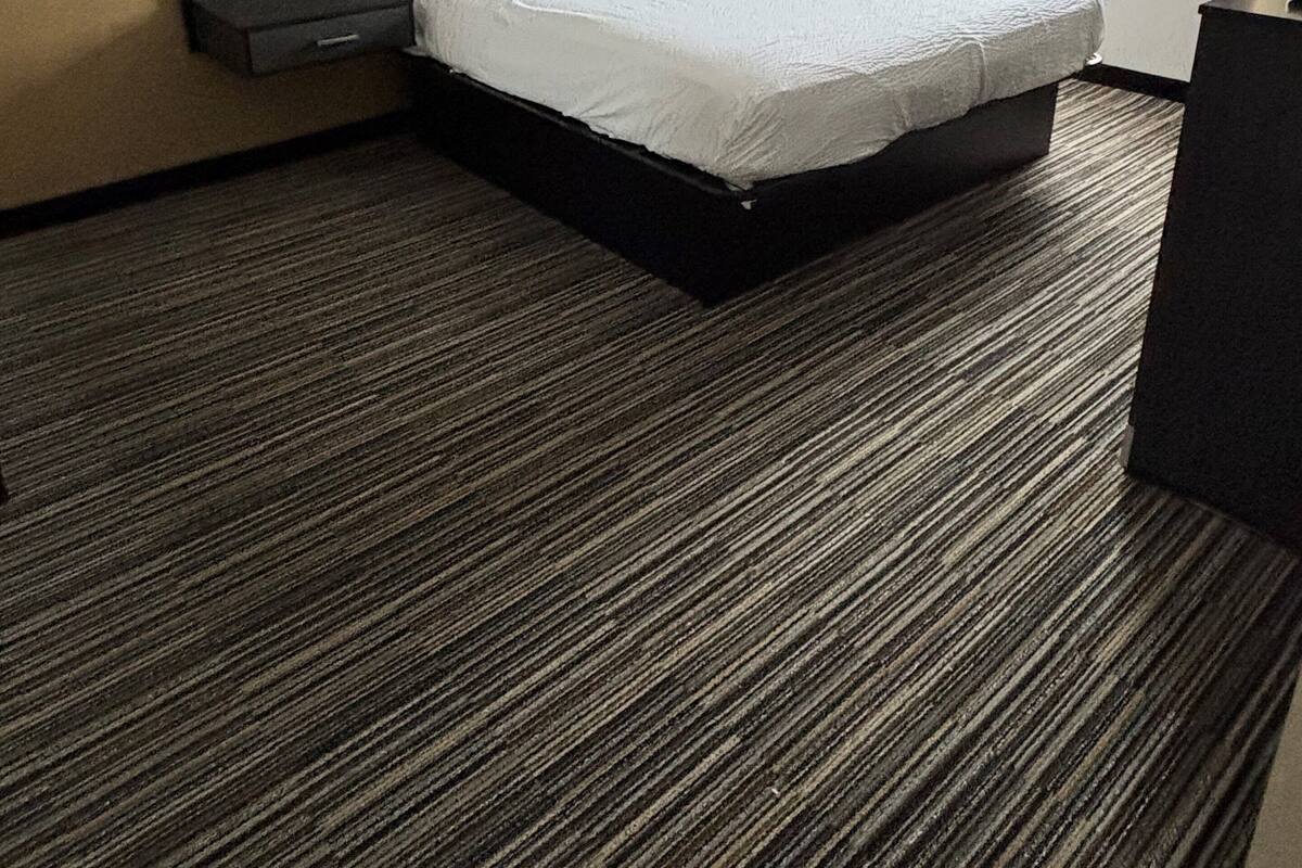 Une chambre d’hôtel avec un grand lit, une table de chevet, une lampe et une fenêtre avec des rideaux.