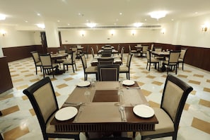 A dining area with multiple tables and chairs, arranged in a semi-circular pattern. - Ramada By Wyndham Jaisalmer Barmer Road (Jaisalmer)