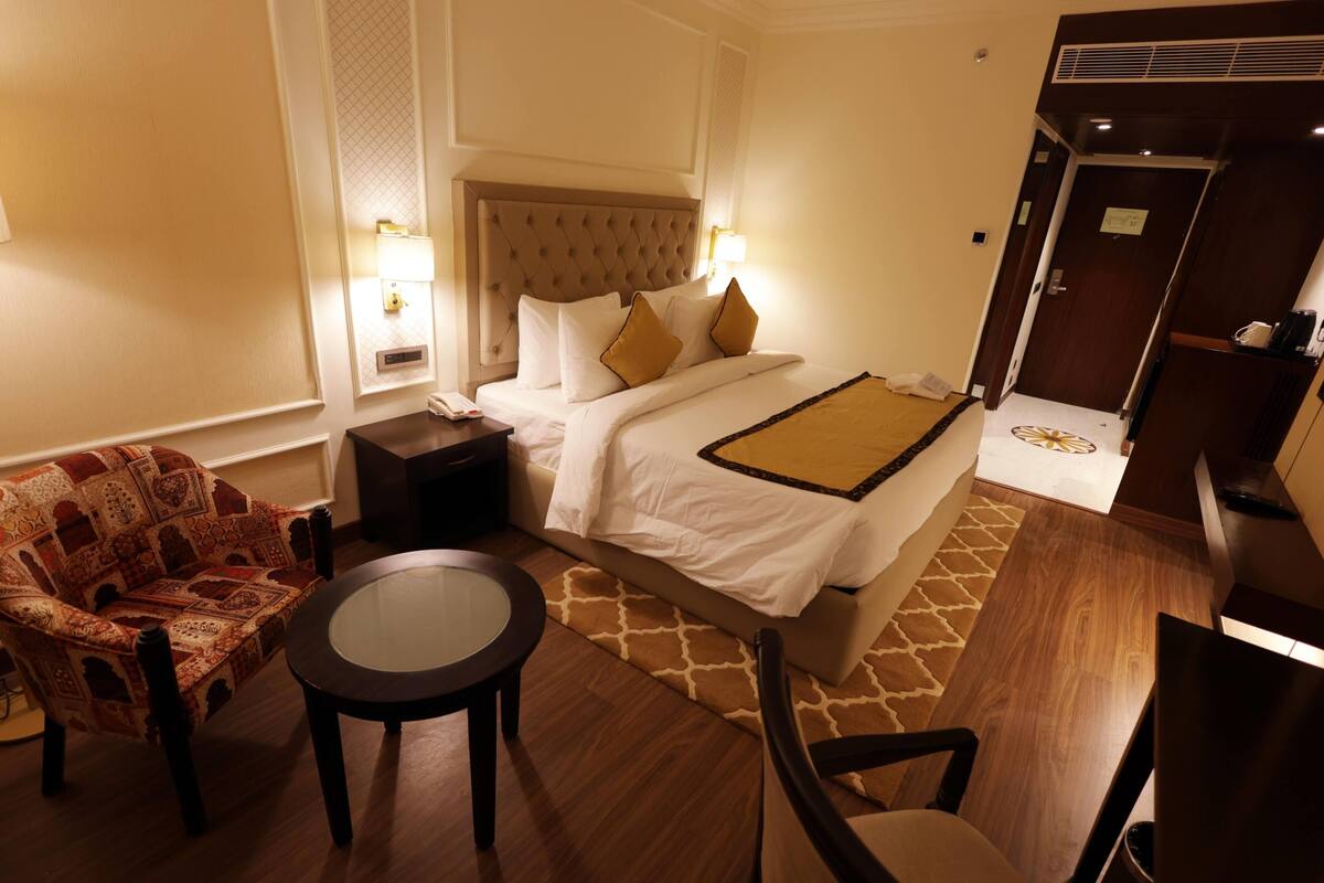Ein Hotelzimmer mit Bett, Stuhl, kleinem Tisch und Nachttisch.