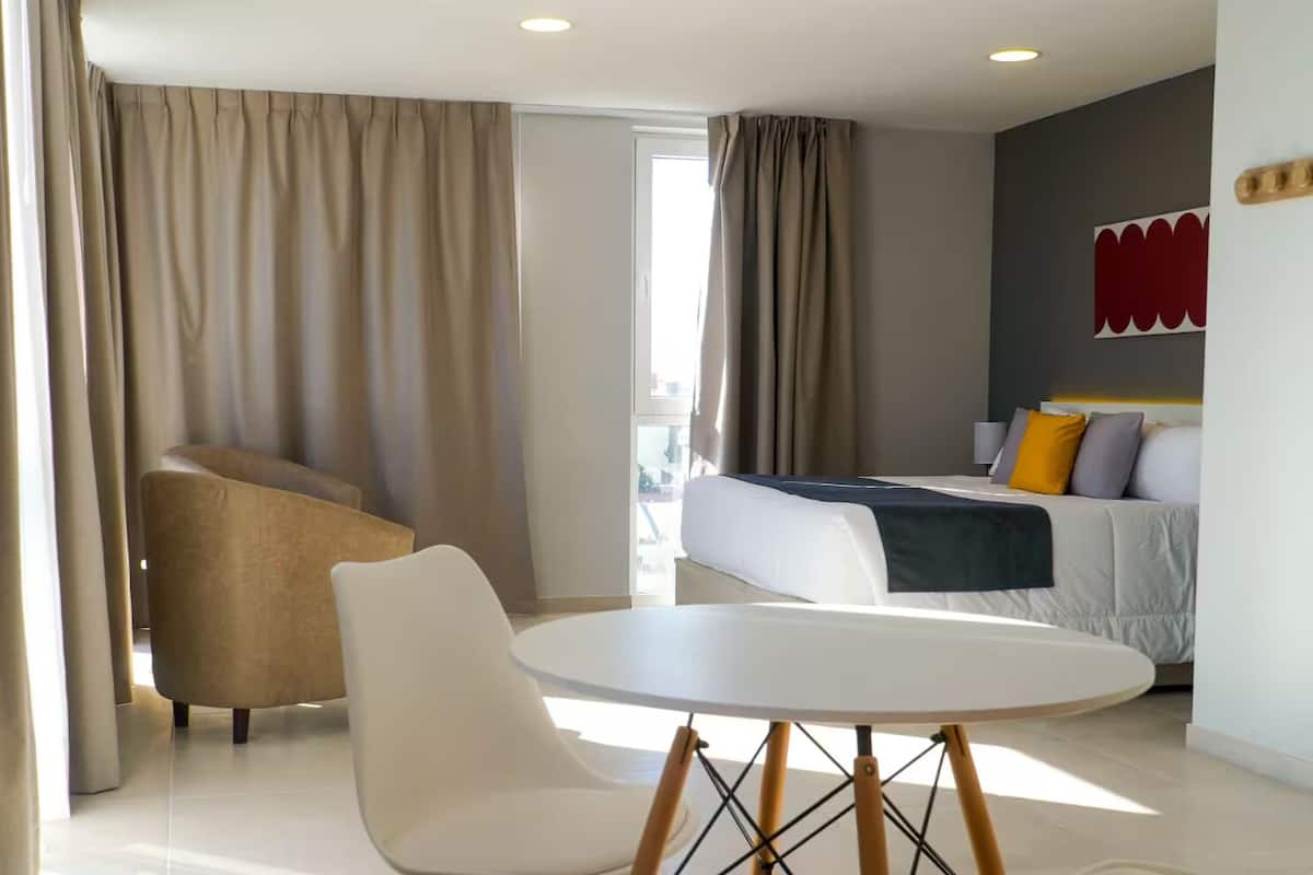 Quarto de hotel com uma cama, uma mesa redonda, uma cadeira e um sofá.