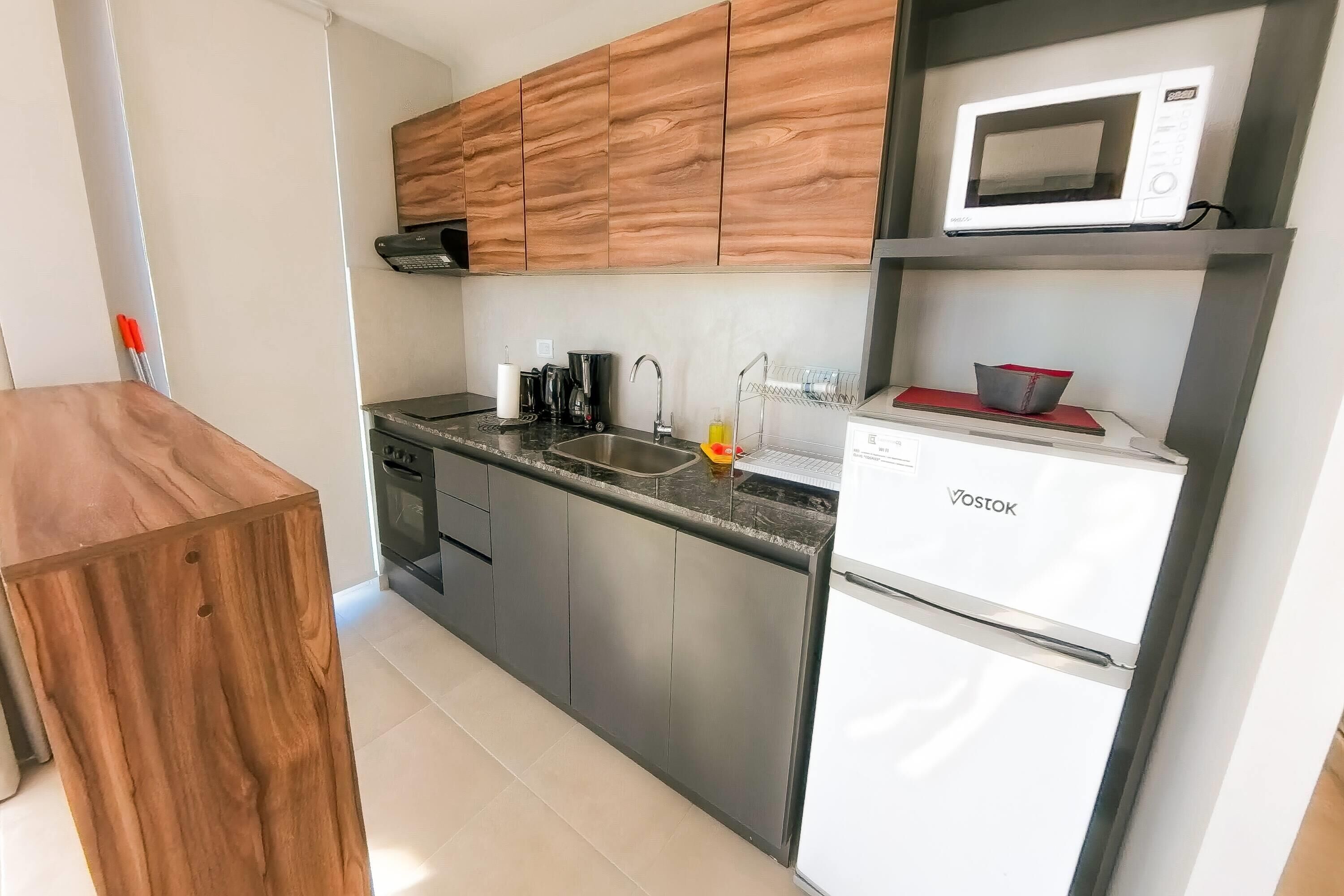 A modern kitchen with wooden cabinets, a built-in microwave, a sink, and a dishwasher.