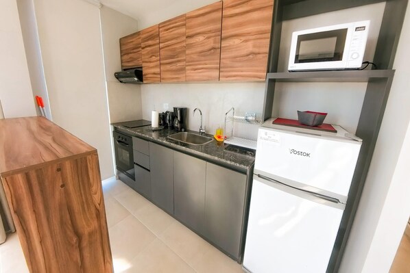 A modern kitchen with wooden cabinets, a built-in microwave, a sink, and a dishwasher.