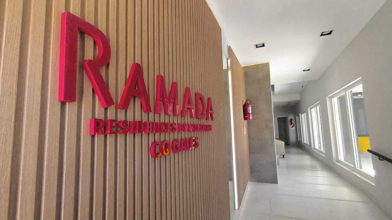 Un passadís amb un cartell de 'RAMADA RESIDENCES BY RAMADA CO. GAMES'.