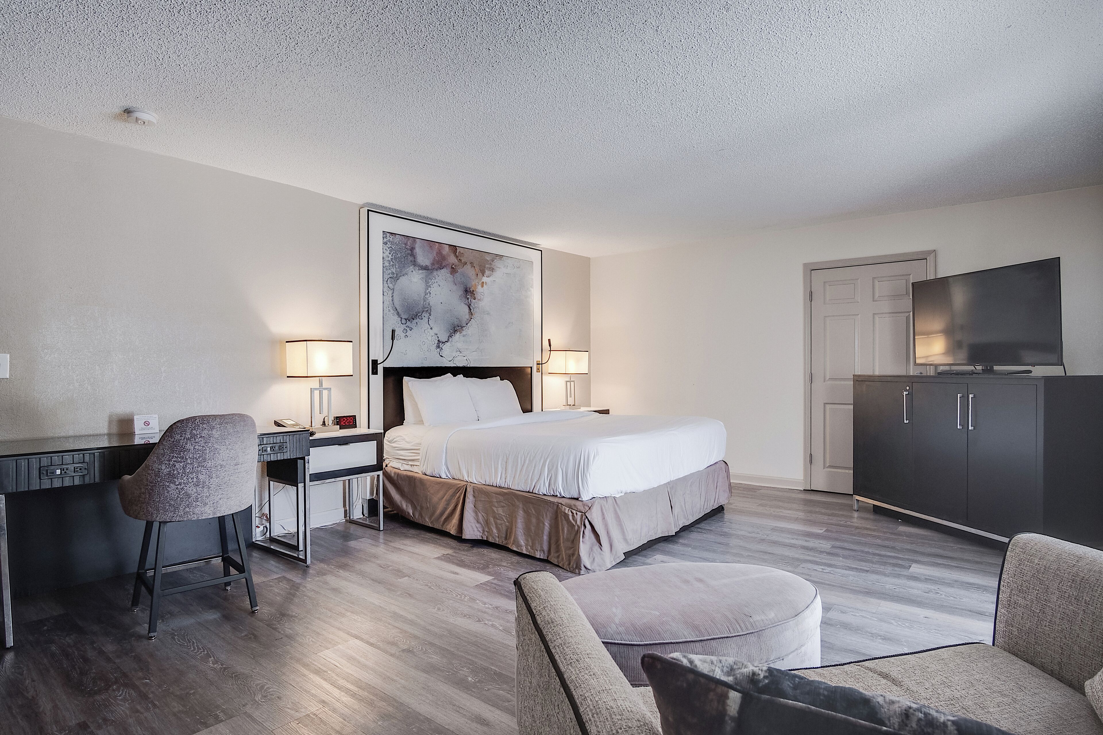 A hotel room with a bed, desk, chair, and a television.