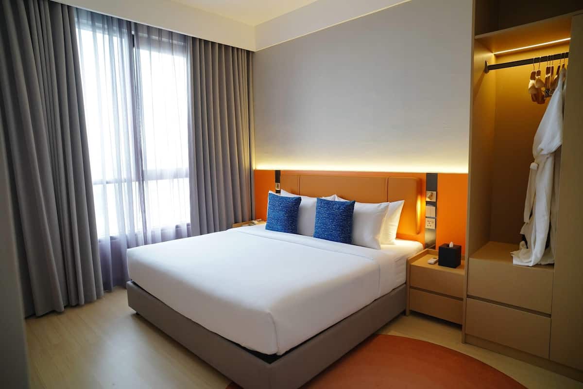 Une chambre d’hôtel moderne avec un grand lit, une table de chevet, une armoire et une fenêtre avec des rideaux.