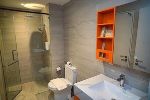 A modern bathroom with a glass-enclosed shower, a white sink, and an orange storage unit. - Wyndham Grand I-City (Shah Alam)