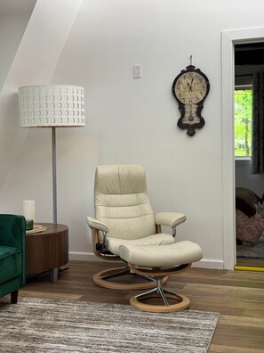 Une pièce comprenant un fauteuil inclinable de couleur crème, une lampe sur pied et une horloge murale.