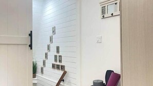 A hallway with a wooden floor, a white door, and a wall-mounted picture frame.