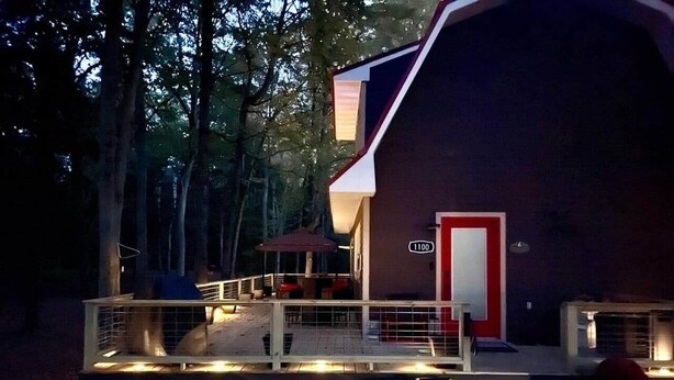 A building with a red door, a number '1100' sign, and a covered outdoor seating area with tables and chairs.