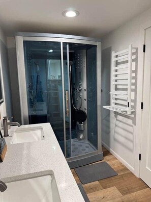 A modern bathroom with a glass-enclosed shower, a white sink, and a towel rack. - 100-Acre Luxury, Dog-Friendly, Sleeps 8-10 (Denver Township)