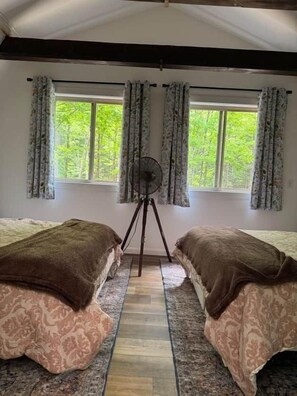 A room with two beds, a standing fan, and a window with curtains. - 100-Acre Luxury, Dog-Friendly, Sleeps 8-10 (Denver Township)