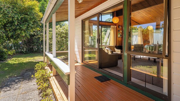 Une terrasse en bois avec une porte vitrée donnant sur un espace extérieur aménagé pour s’asseoir.