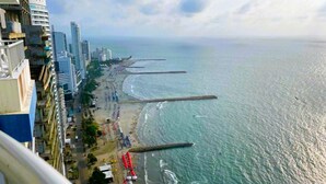 Un paysage urbain côtier avec de hauts immeubles, une plage et une jetée qui s’avance dans l’océan.
