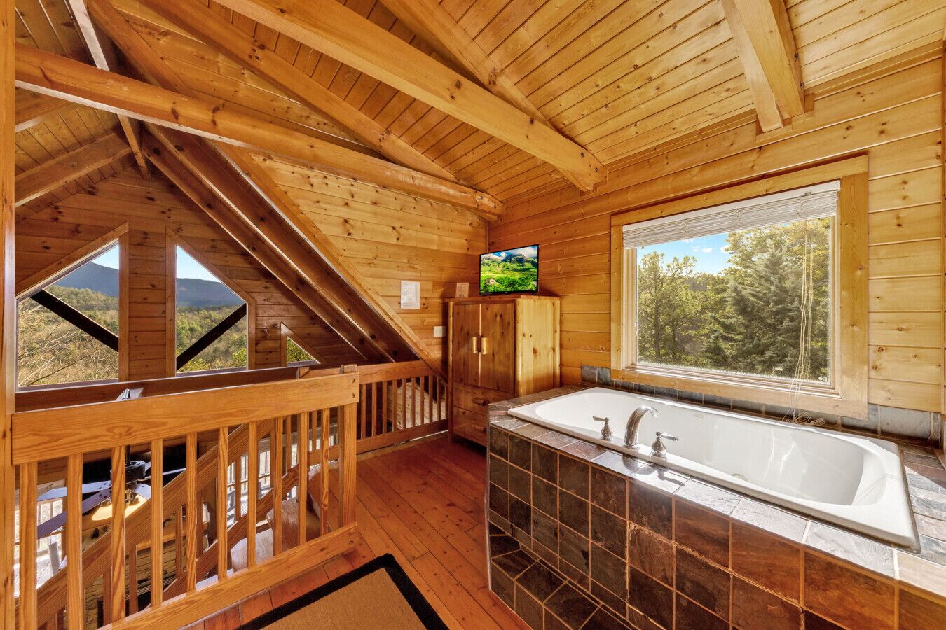 A wooden cabin interior with a bathroom, a TV, and a view of the outdoors.