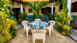 A patio with a round table and four chairs, surrounded by gravel and various plants.