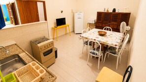 Eine kompakte Küche mit Gasherd, Backofen, Spüle und einer Essecke mit Tisch und Stühlen.