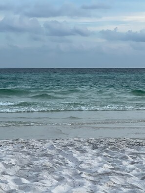 Une plage avec des vagues et un ciel nuageux.