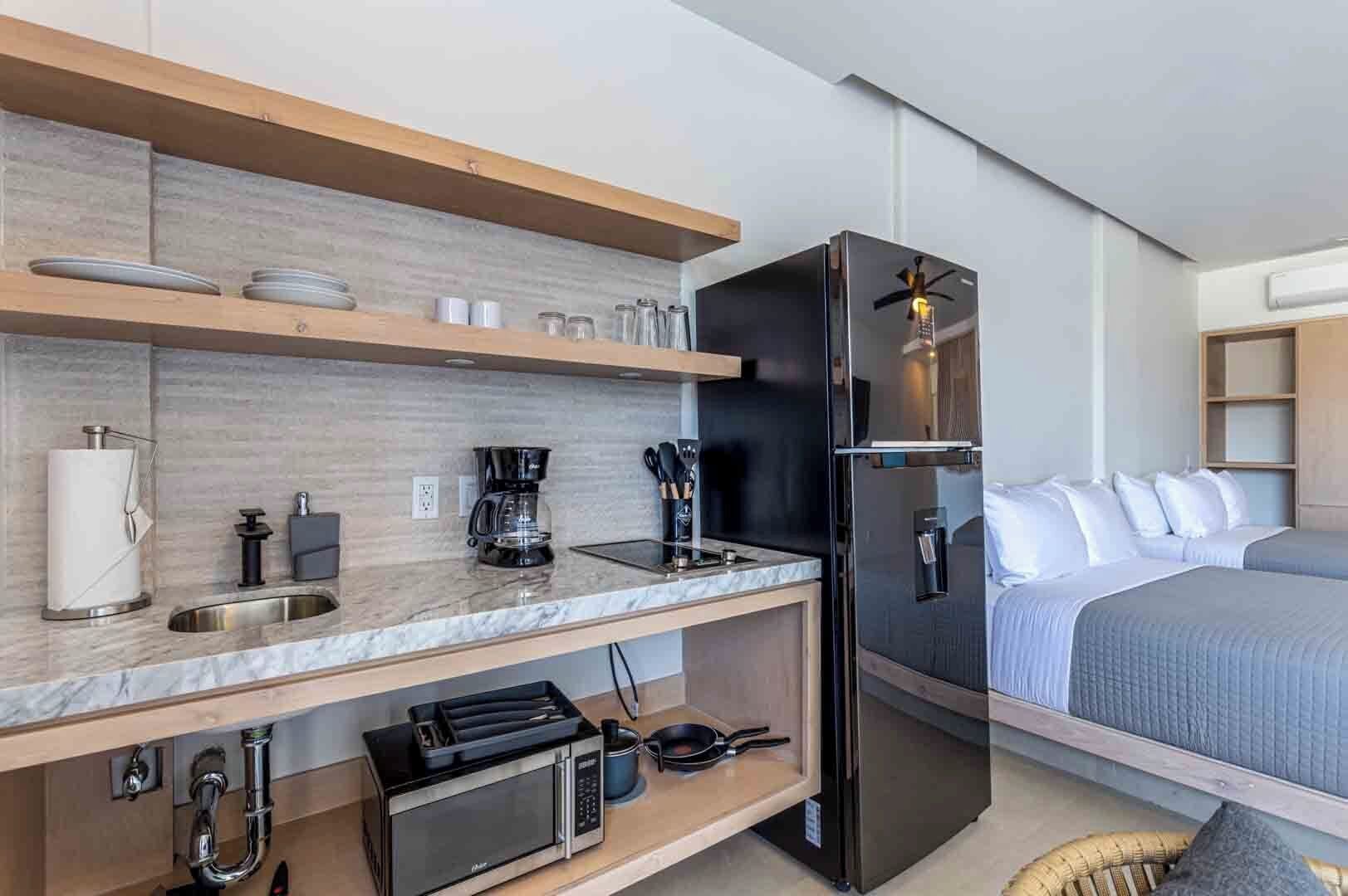 Ein kleines Hotelzimmer mit Küchenzeile, einem Bett und einer kleinen Sitzecke.