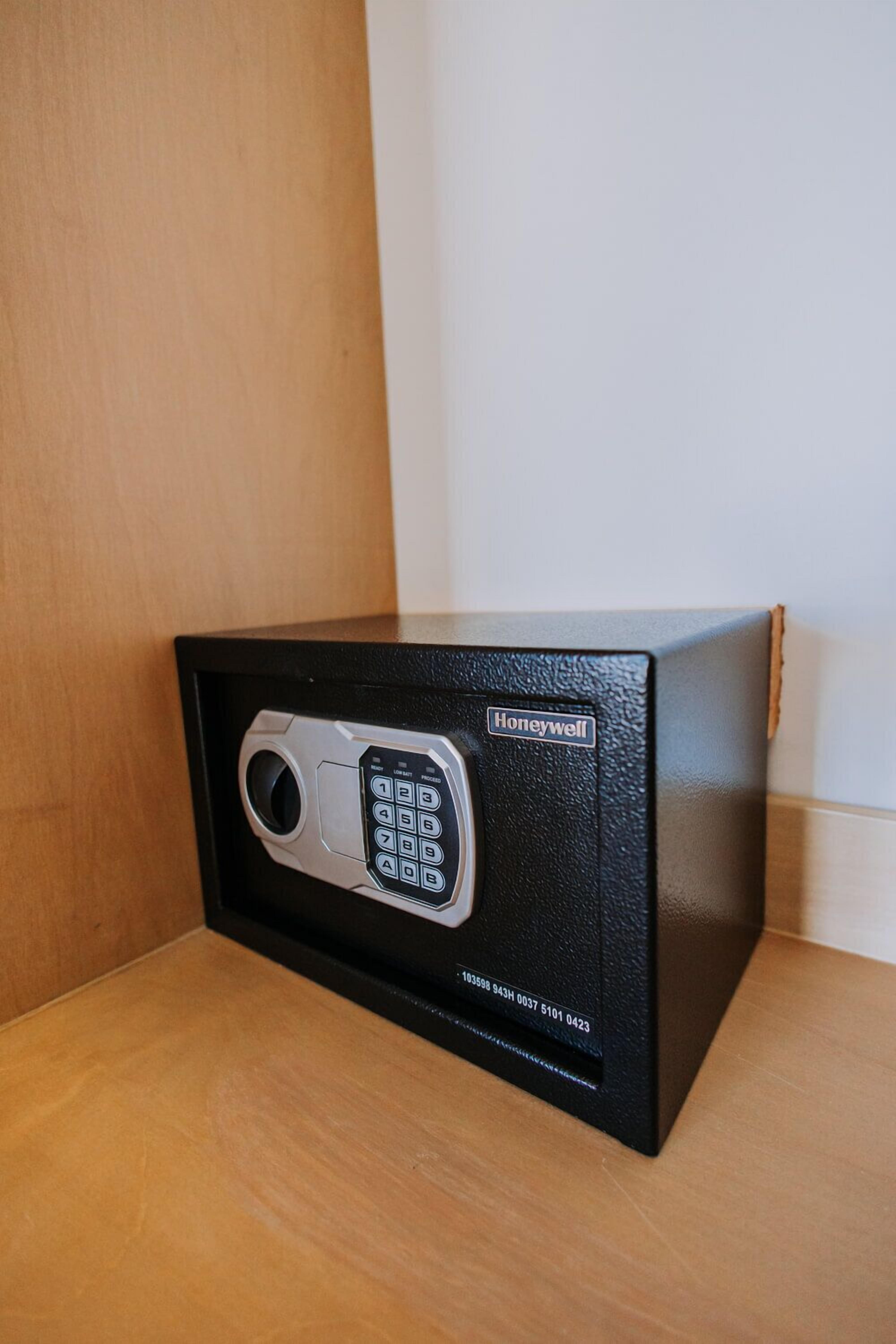 A Honeywell safe with a keypad, placed on a wooden surface against a wall.