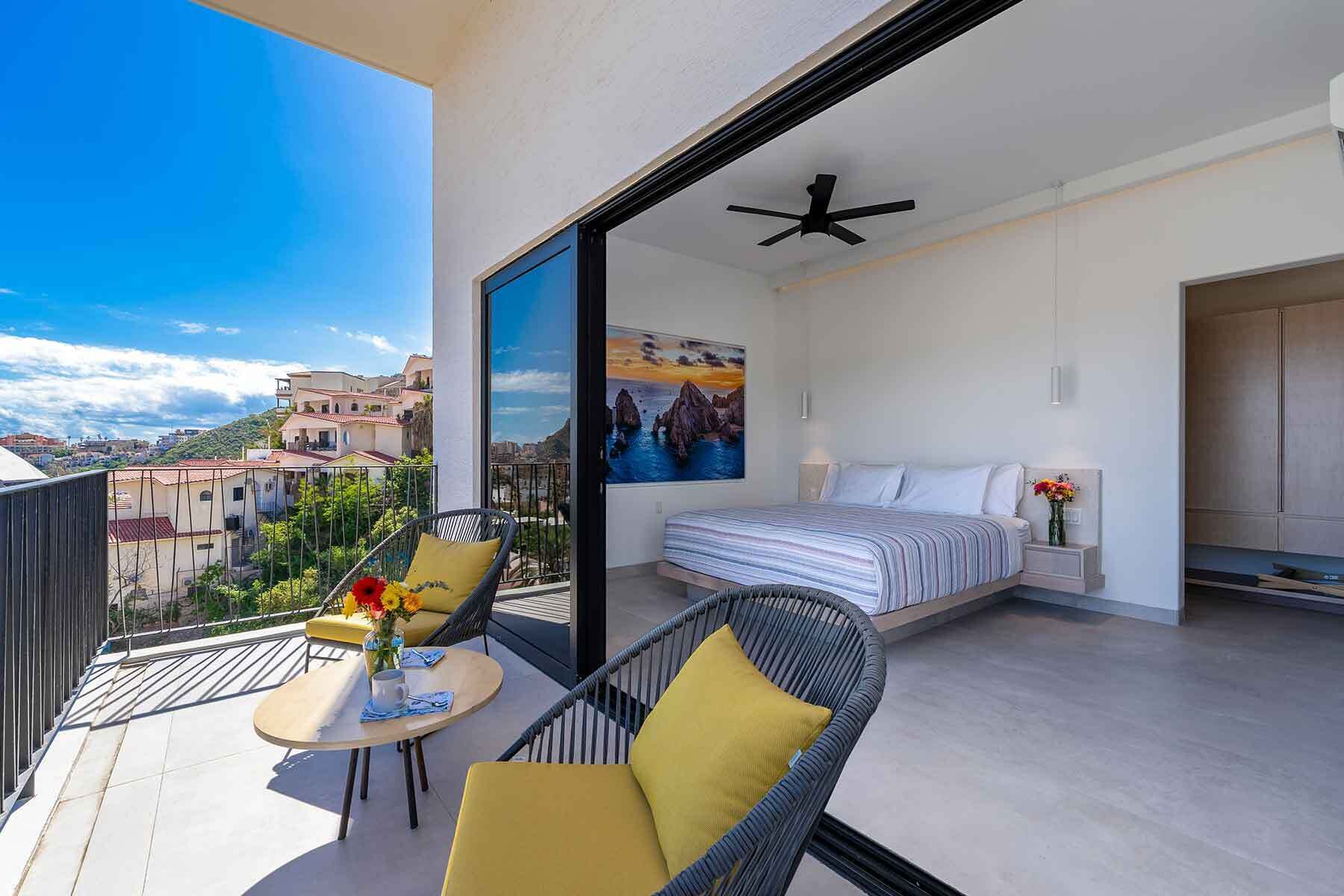Ein Balkon mit Bett, Stuhl, Tisch und einem Gemälde.