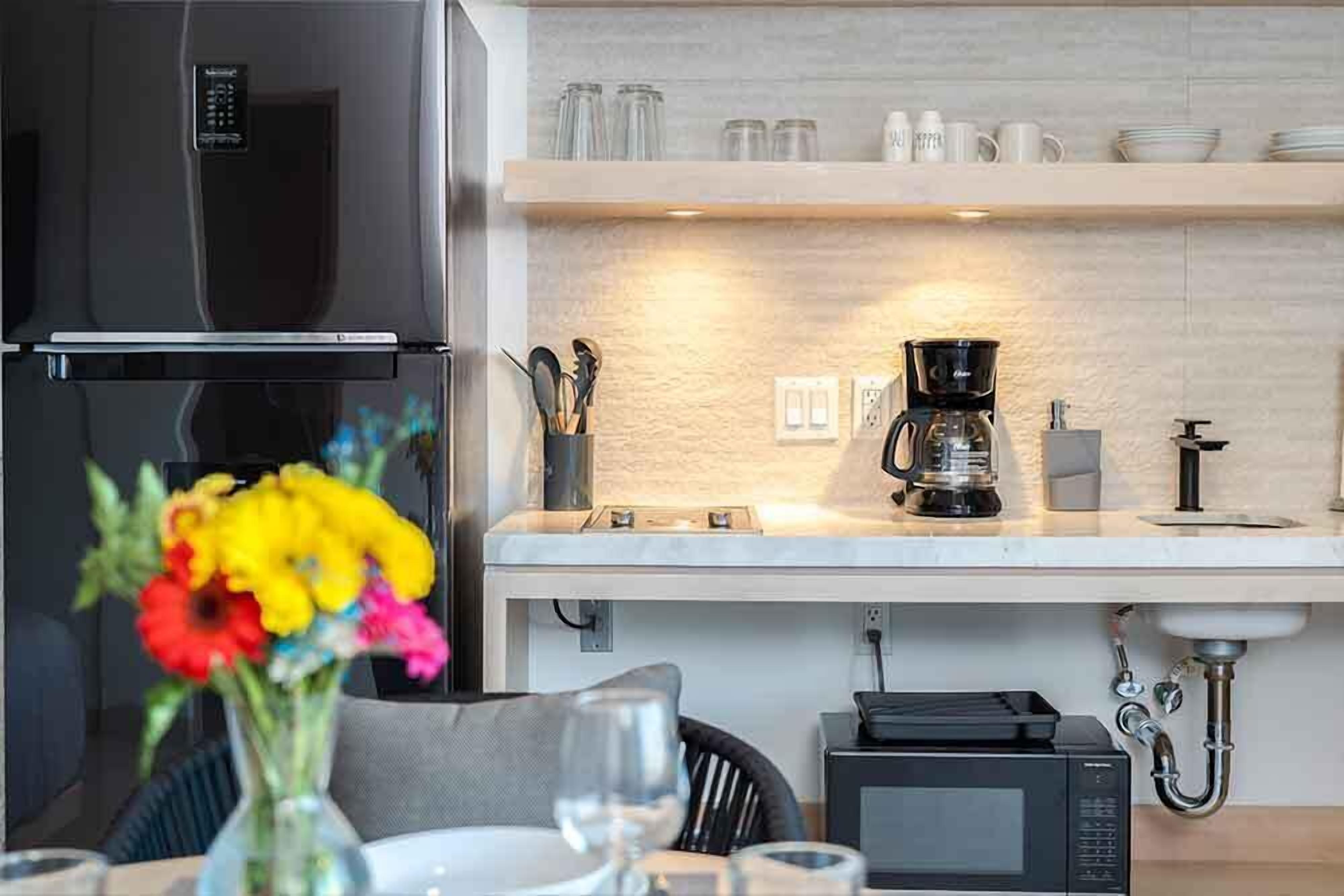 A modern kitchen with a stainless steel refrigerator, a coffee maker, and a microwave on the countertop.