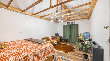 A bedroom with a bed, a sofa, a massage chair, a water dispenser, and a plant.