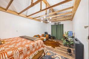 A bedroom with a bed, a sofa, a massage chair, a water dispenser, and a plant.