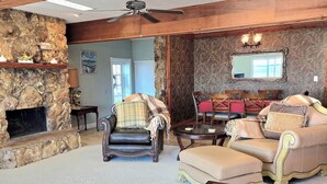 A spacious living room with a stone fireplace, a ceiling fan, and a large mirror on the wall. - Lake Eustis Waterfront Sunset House 3/2 Amazing Views! Boat Dock Available!  (Eustis)