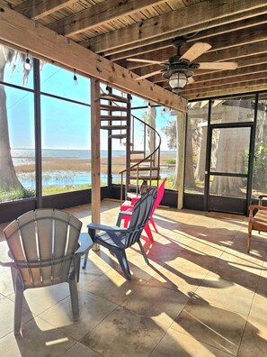 Un espacio de estar al aire libre cubierto con techo de madera, una escalera en espiral y vistas a la playa.