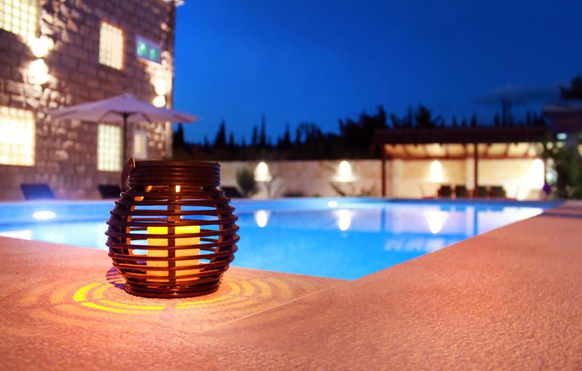 A poolside area with a decorative lantern and a building in the background.