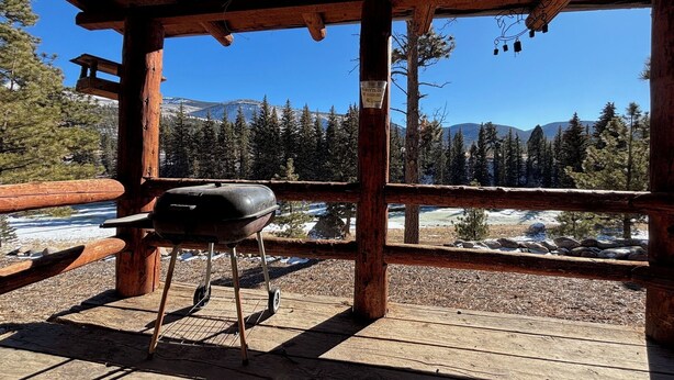 A wooden deck with a grill, overlooking a snowy landscape and forested mountains. - Mountain cabin with river views Sleeps 4. 15 minutes from Wolf Creek Ski Area. (South Fork)