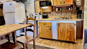 A compact kitchen with wooden cabinets, a microwave, a refrigerator, a sink, and a wooden dining table with chairs. - Mountain cabin with river views Sleeps 4. 15 minutes from Wolf Creek Ski Area. (South Fork)