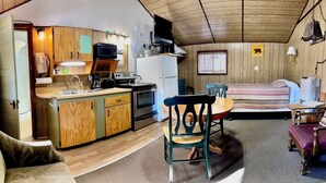 Interior compacto de una caravana con kitchenette, zona de comedor y zona de dormir.