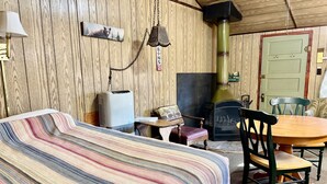 Una habitación acogedora con cama, una mesa con sillas, chimenea y una lámpara de pared.