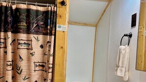 A bathroom with a wooden floor, a white toilet, a sink with a black faucet, and a shower curtain with a fish pattern. - Great mountain cabin with river views. Sleeps 4. 15 miles to Wolf Creek Ski area and 3/4 mile private fishing. (South Fork)