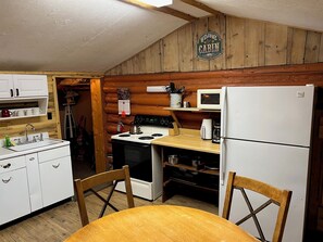 A cabin kitchen with a stove, sink, refrigerator, and wooden cabinets. - Mountain cabin with river views . Sleeps 6.15 minutes from Wolf Creek Ski Area. (South Fork)