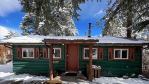 A log cabin with a wooden door, windows with shutters, and a chimney. - Mountain cabin with river views sleeps 8 . 15 minutes from Wolf Creek Ski Area. (South Fork)