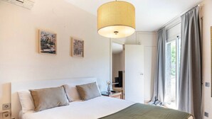 Una habitación de hotel con una cama grande, una lámpara colgante y dos cuadros en la pared.