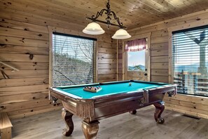 A wooden-paneled room with a pool table, two windows with blinds, and a chandelier. - Sevierville Views • Hot Tub • Theater • Pets OK (Sevierville)