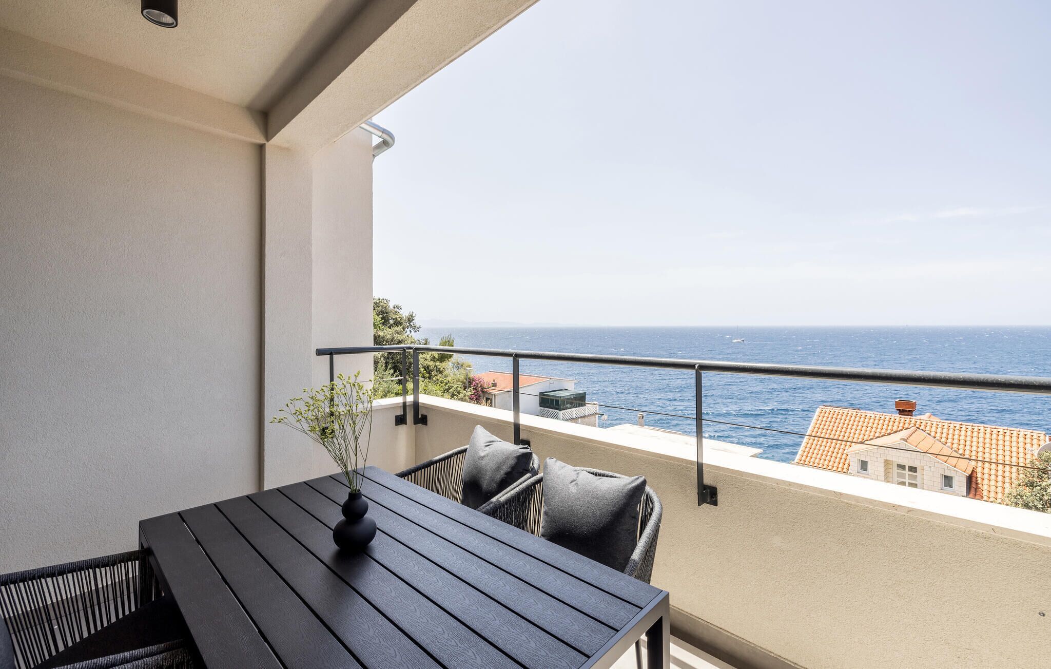 Un balcon avec une table et des chaises, donnant sur la mer.