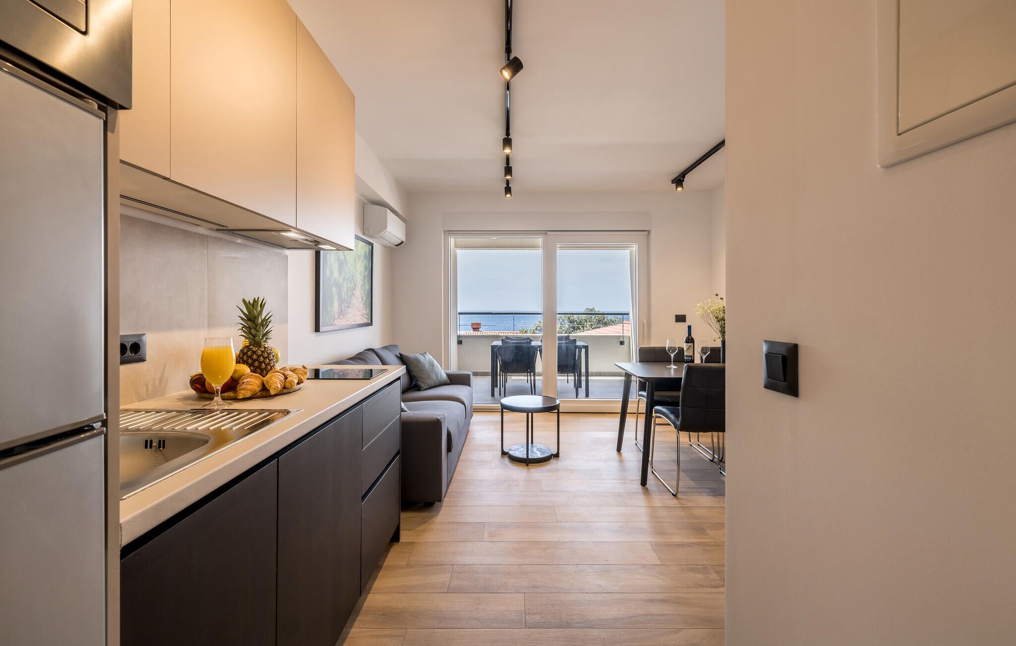 A modern kitchen with a large island, a dining area with a view, and a balcony with a table and chairs.