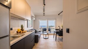 Eine moderne Küche mit einer großen Kochinsel, einem Essbereich mit Blick und einem Balkon mit Tisch und Stühlen.