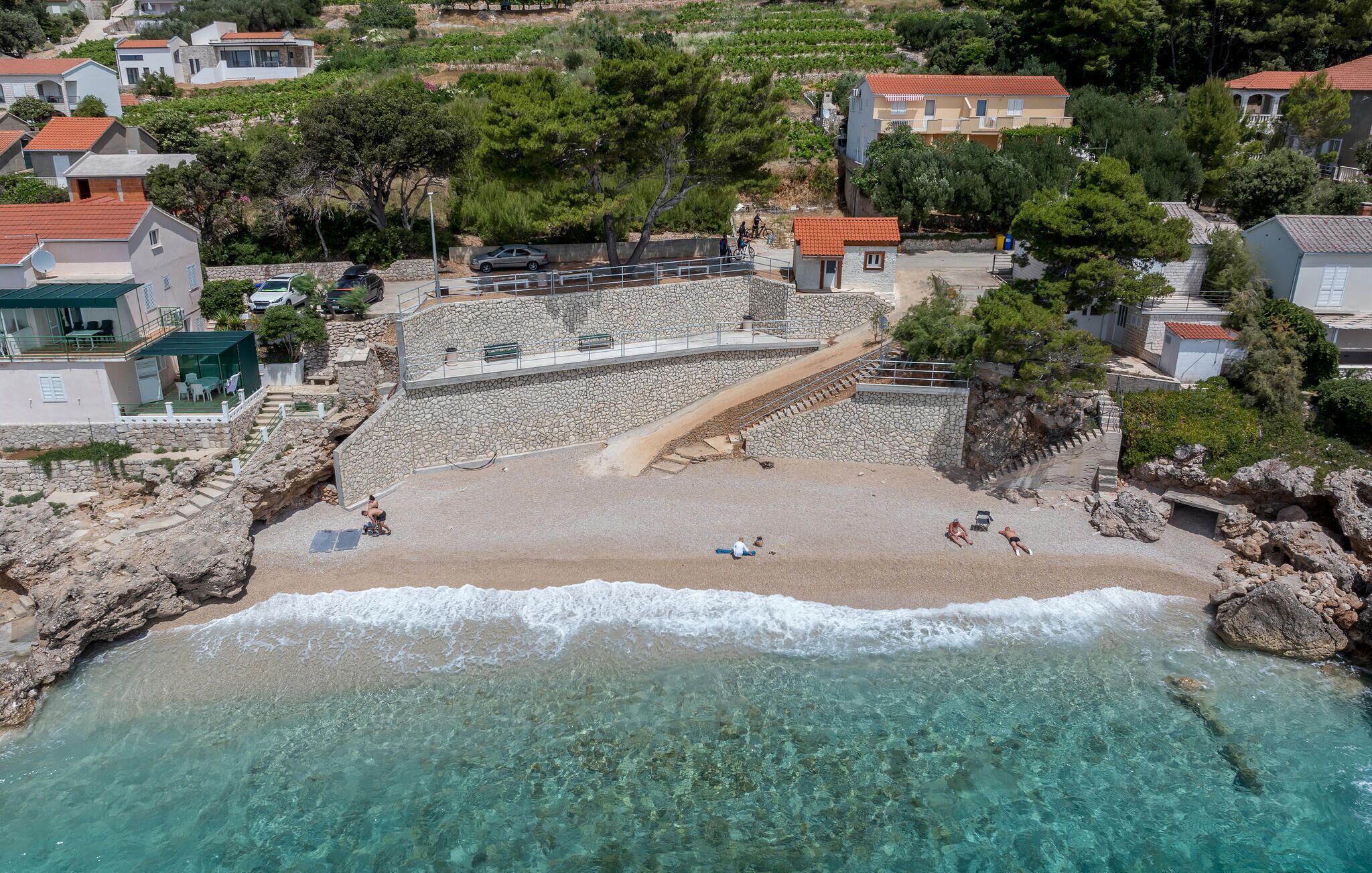 Une zone côtière dotée d’un escalier en pierre menant à une plage, entourée d’immeubles résidentiels et de verdure.