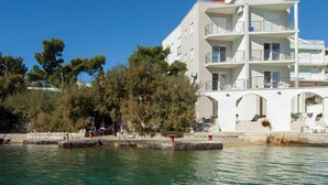 A multi-story white building with balconies, located near a body of water. - 1 bedroom awesome apartment in Klek (Klek)